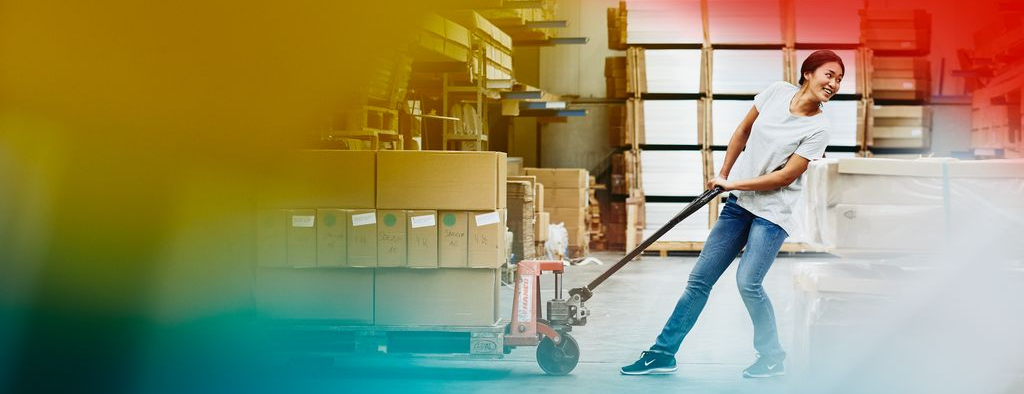 Female blue-collar worker operating a pallet loader. Primary colors yellow and red.
